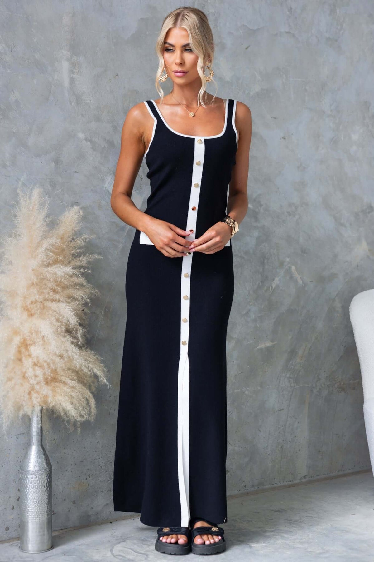 Model wearing Qulver Maxi Dress, featuring faux buttons, pockets, front split, ribbed knit material, in a stylish black design.