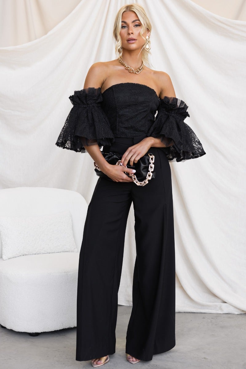 Model wearing Ruxton Top, a black strapless top with tulle sleeves and wide-leg pants, showcasing a stylish look.