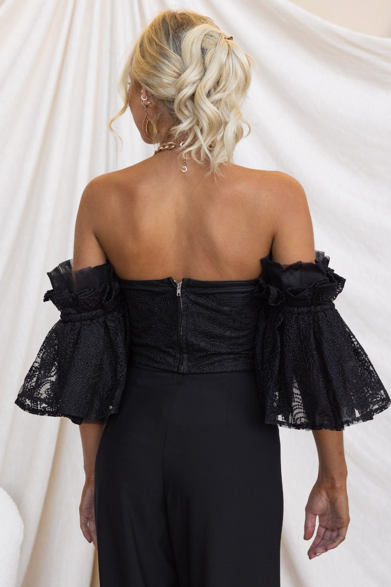Back view of the Ruxton Top, a black strapless design with tulle underlay and flared sleeves, showcasing its zip closure.