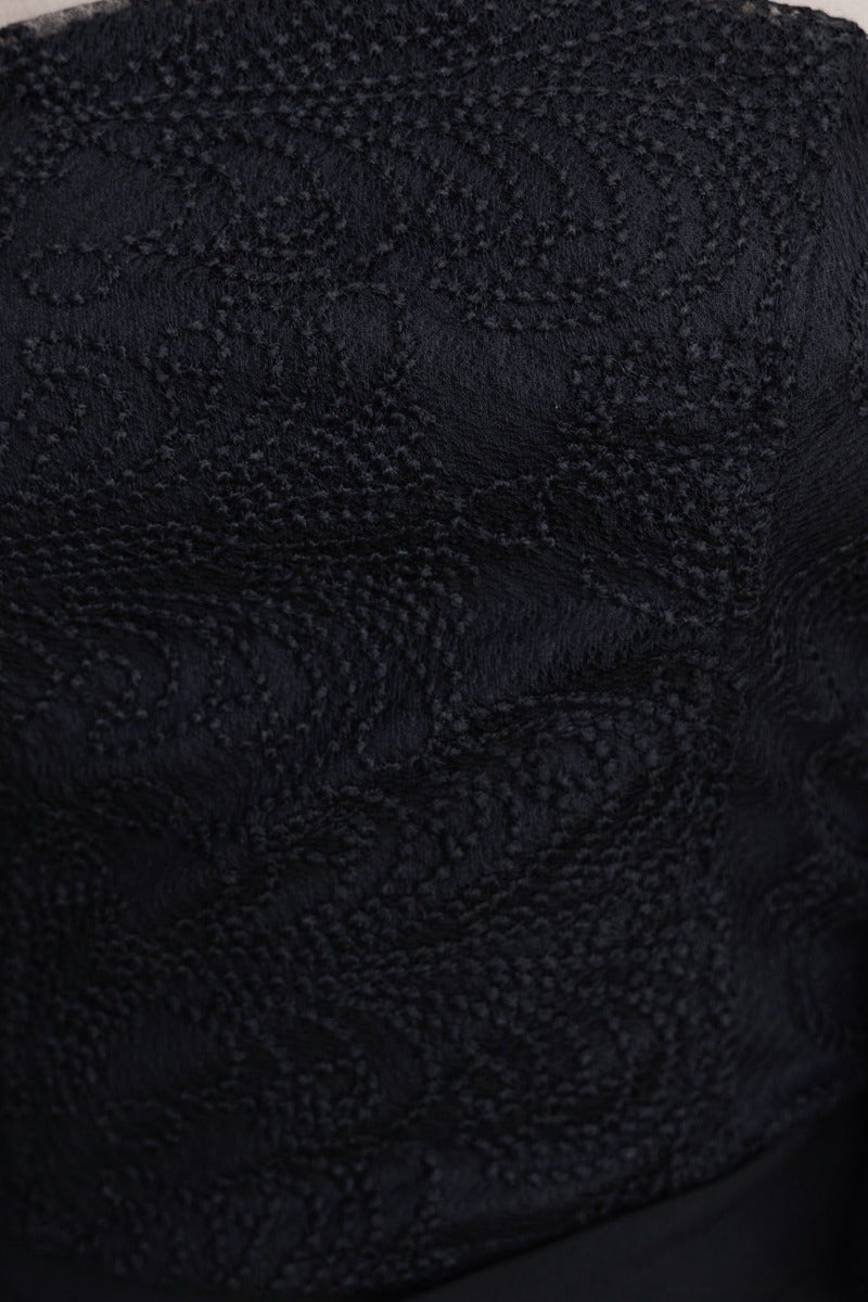 Close-up of Ruxton Top's textured black fabric featuring intricate patterns, showcasing its elegant design details.