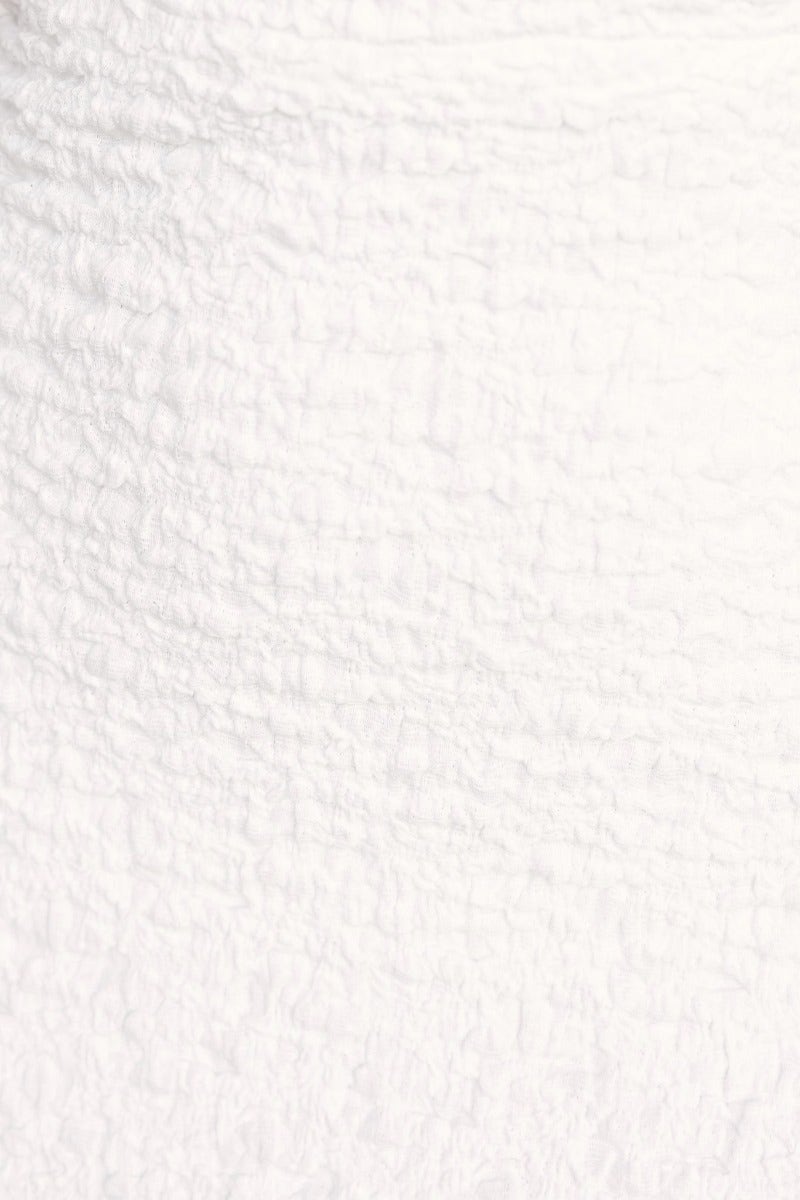 Close-up of textured white fabric for a strapless Hollywood maxi dress.
