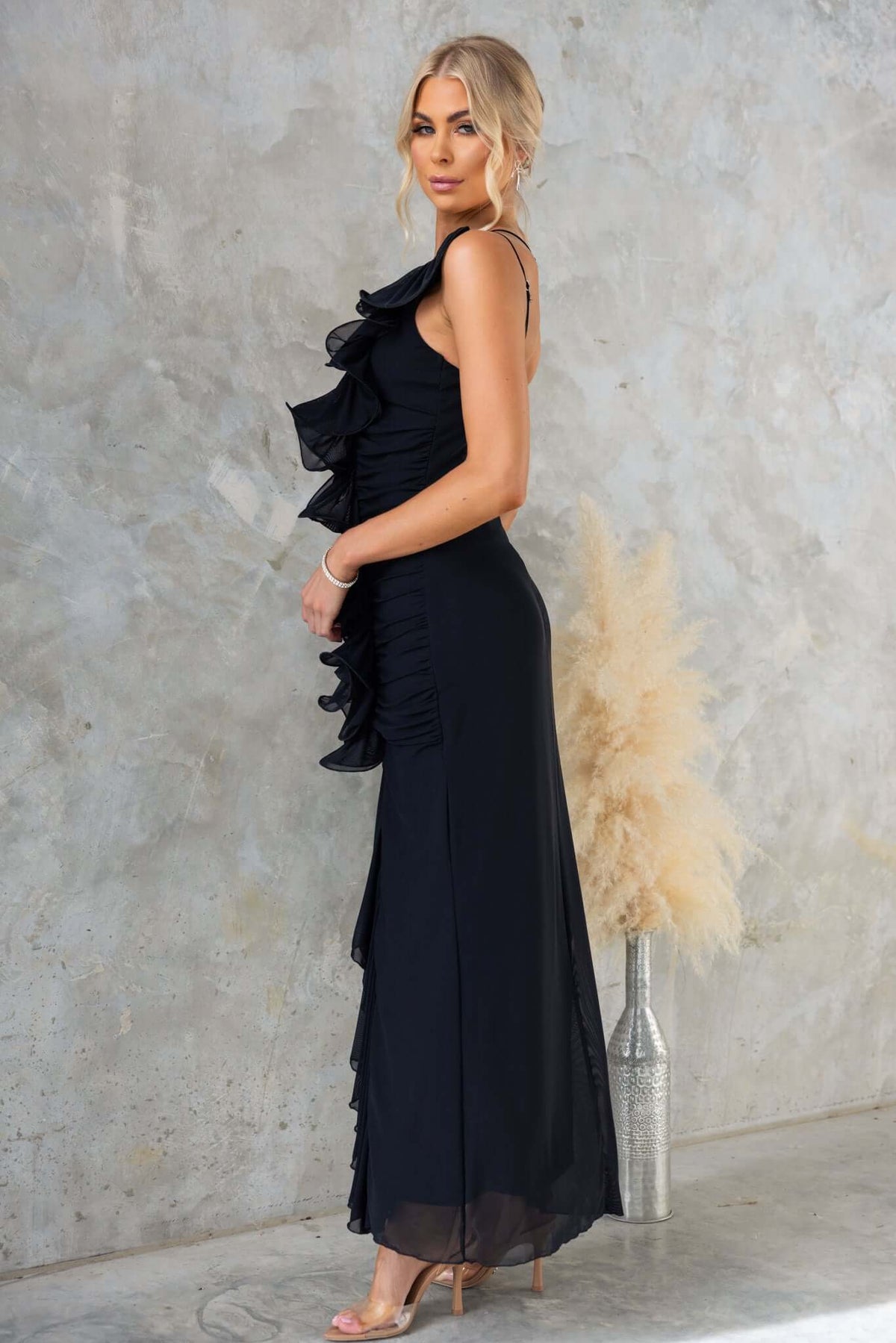 Rehna Maxi Dress in black with one-shoulder design and ruffles, featuring a high-low hem and adjustable straps.