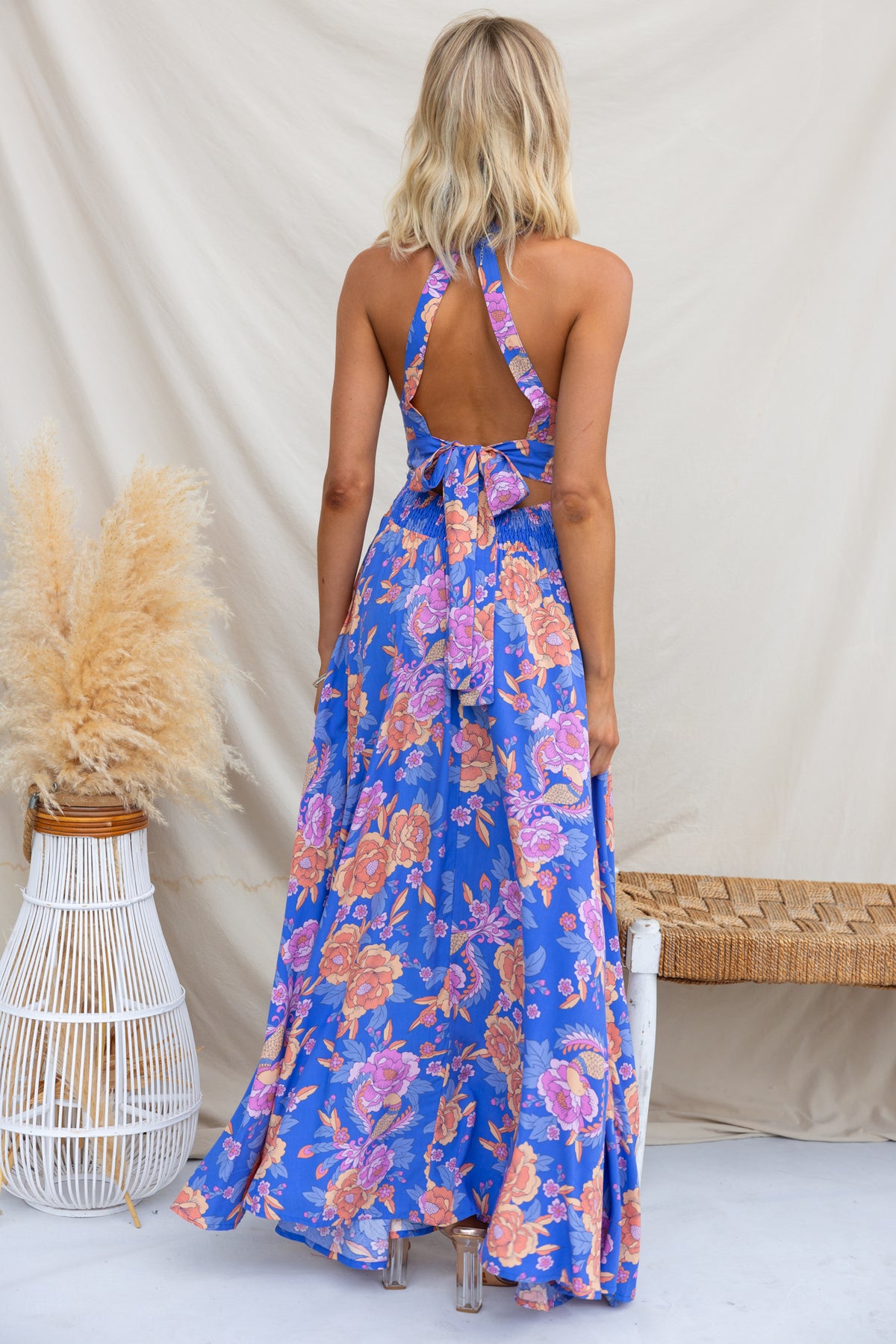 Back view of Relly Maxi Dress featuring a high halter neckline and vivid floral pattern in blue and orange.