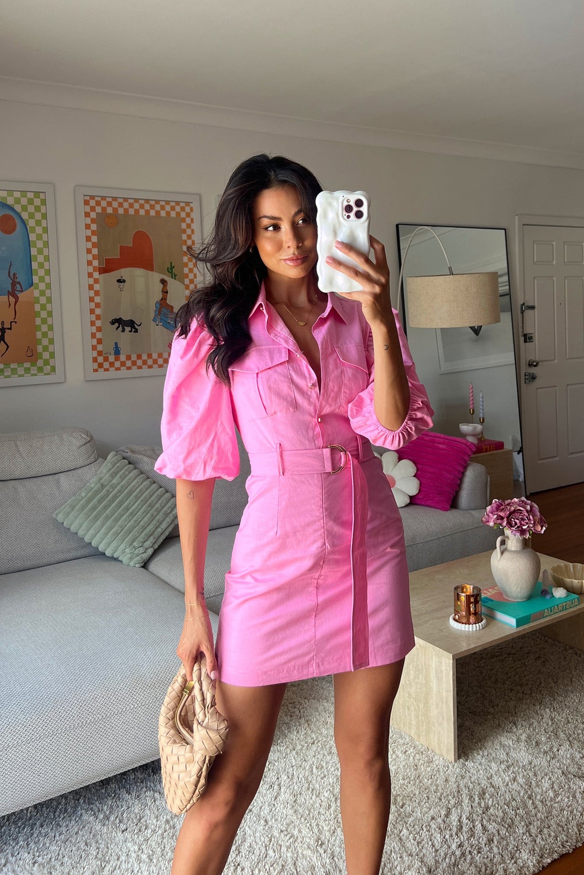 Model wearing a pink Astyn Dress with a collar, puff sleeves, and belt, styled in a bright living room.