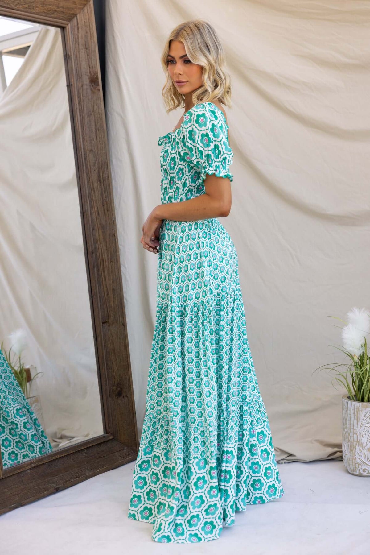 Model wearing the Right Time Maxi Dress, featuring a floral pattern and elastic bodice, shown against a mirror backdrop.