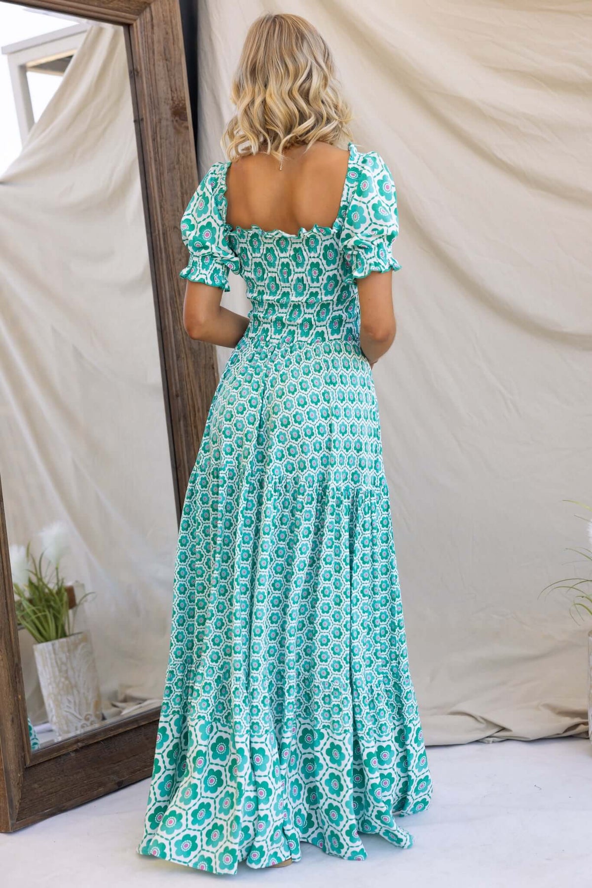 Back view of Right Time Maxi Dress featuring elastic bodice, puff sleeves, and floral pattern in teal color.