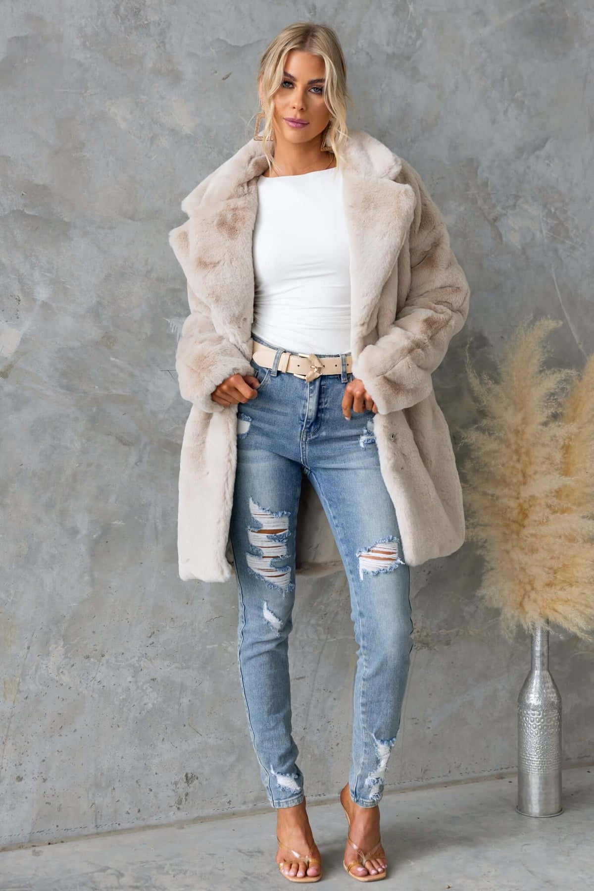 Model wearing the Runey Coat, a fluffy lined coat with collar, buttons, and pockets, styled with ripped jeans.