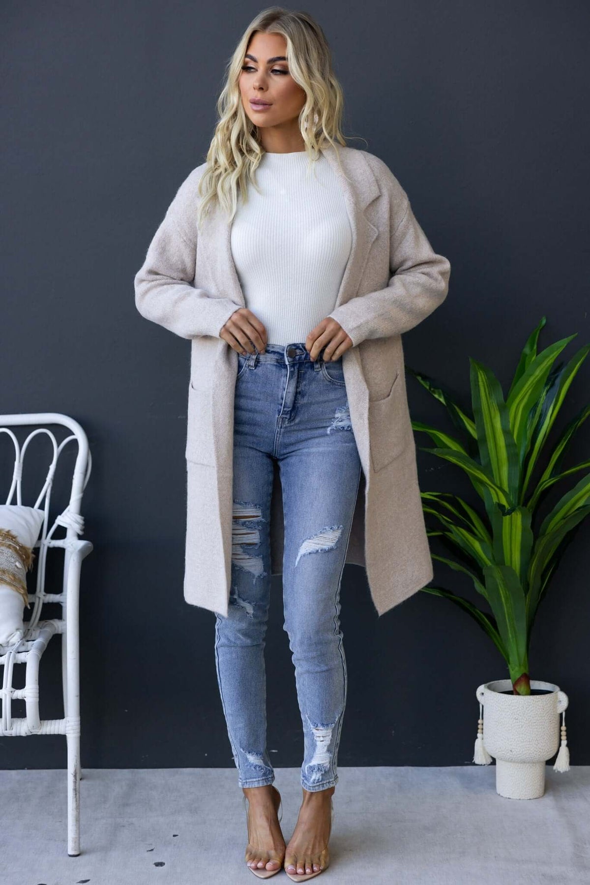 Model wearing Sarlia Cardigan with collar and pockets, paired with ripped jeans, showcasing a relaxed fit and knit fabric.