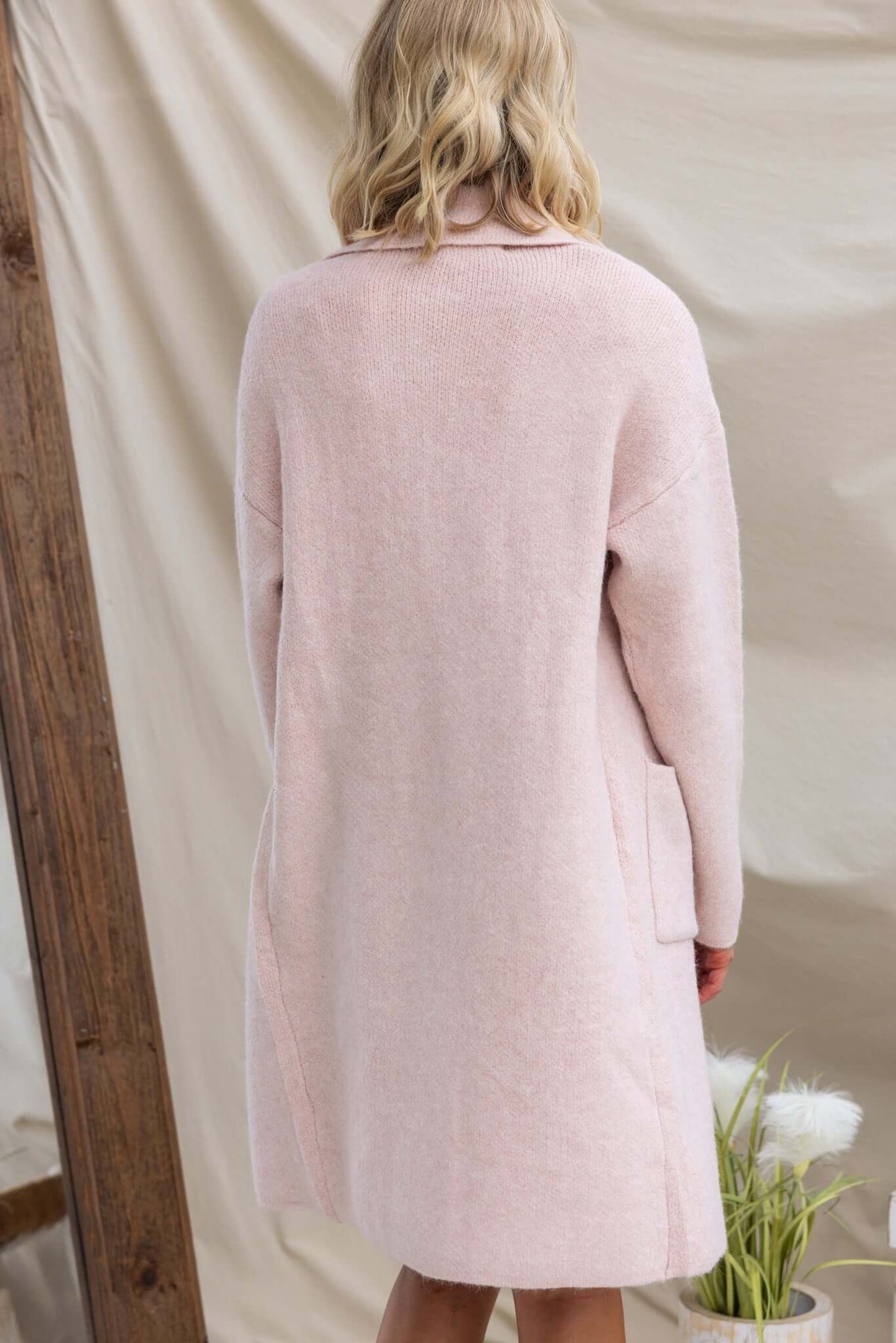 Elegant pink Sarlia Cardigan featuring a collar, pockets, and a cozy knit design, worn from the back.