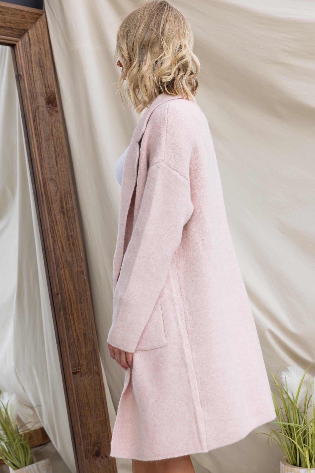 Pink Sarlia cardigan featuring a collar and pockets, shown side view on a model in a casual setting.