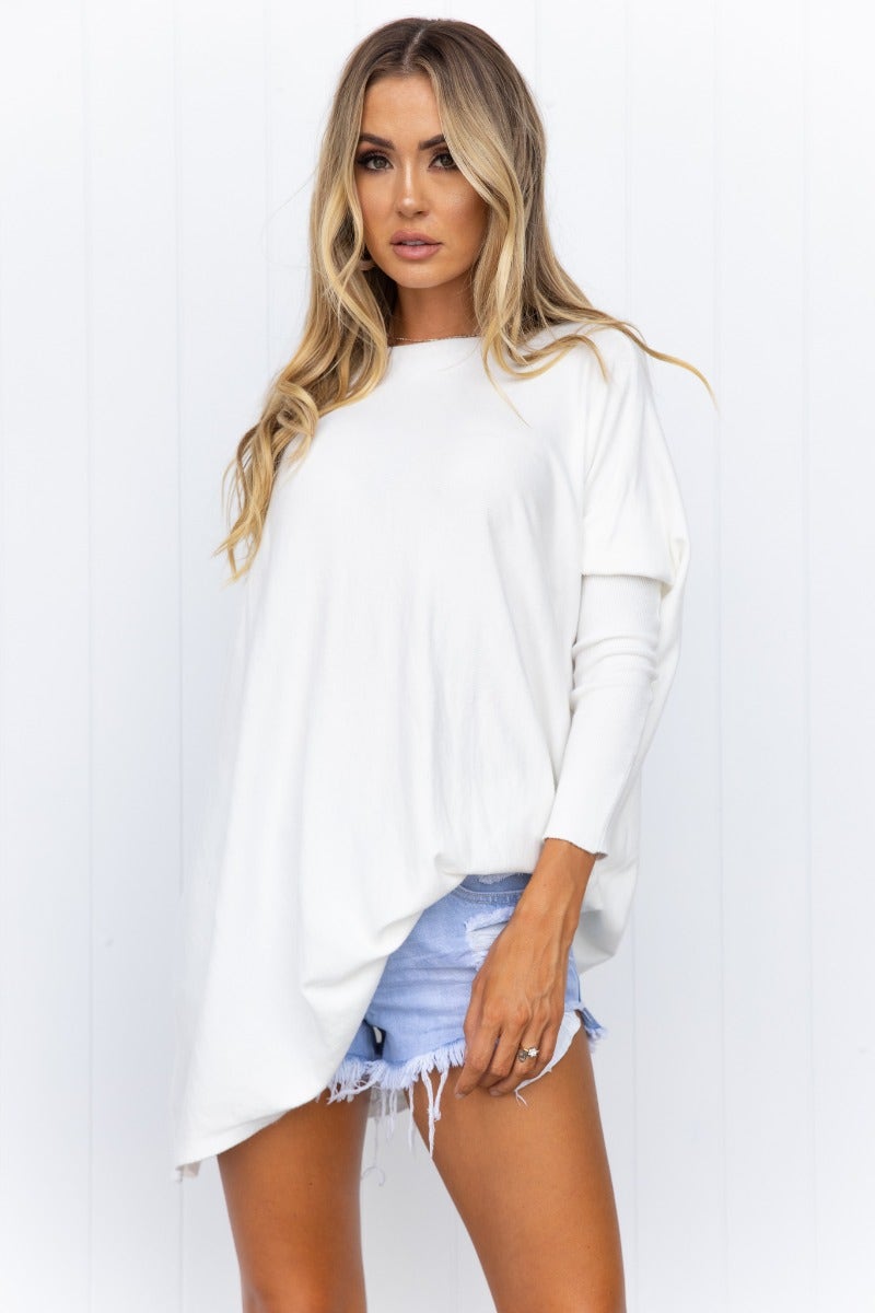 Model wearing a cozy oversized Bonnie Knit top, featuring full-length sleeves and relaxed fit, paired with denim shorts.