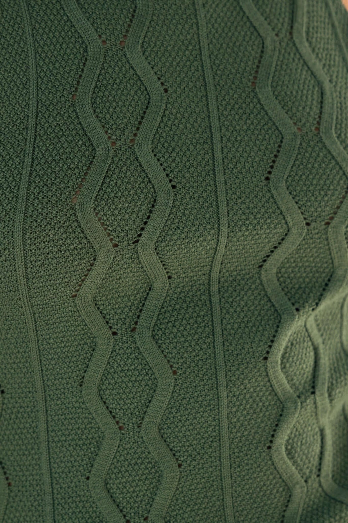 Close-up of green cable knit fabric with a wavy pattern, showcasing texture and stretch of the Shannon Bodysuit.