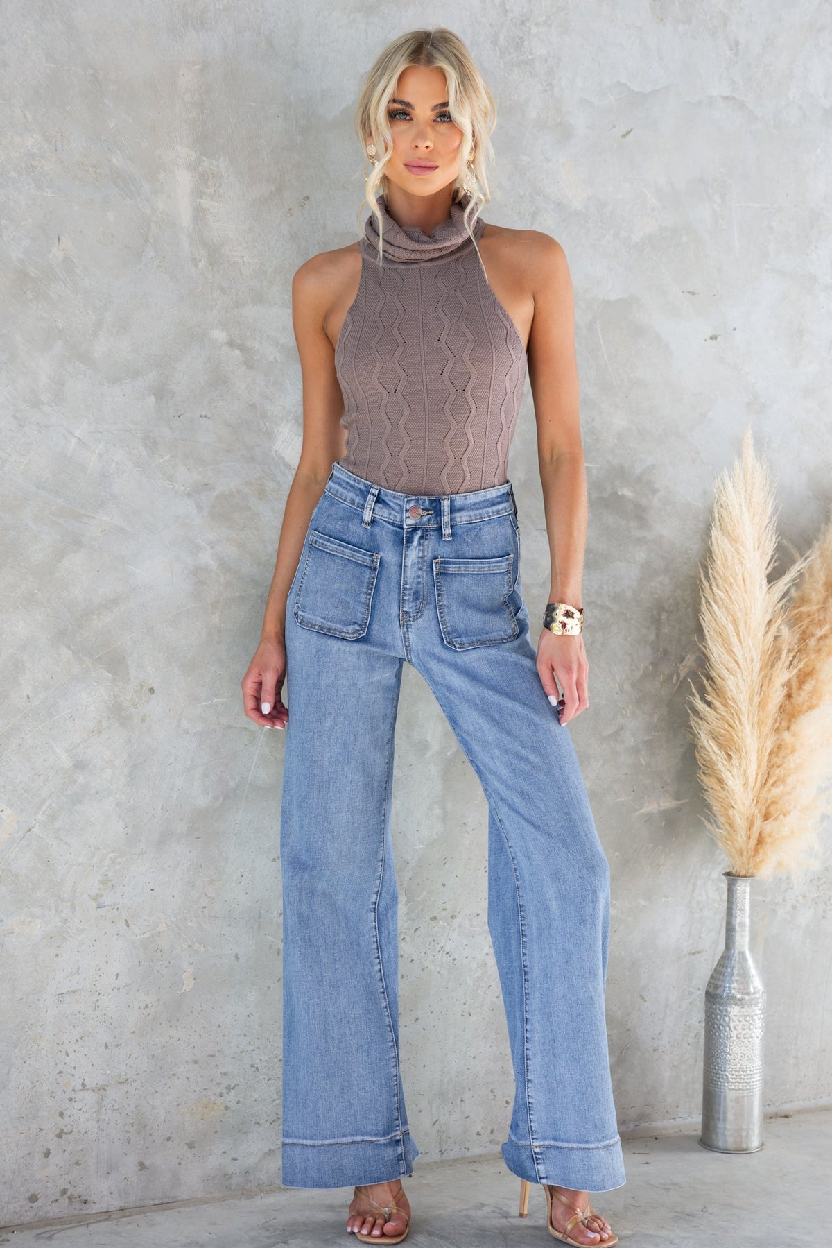 Shannon bodysuit with turtle neckline, cable knit design, paired with wide-leg jeans, model standing against gray background.