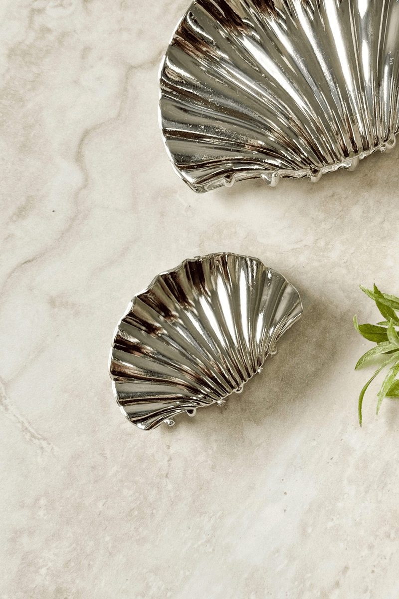 Shore Claw Clip with a metallic finish, 6cm in length, displayed on a marble surface with greenery.