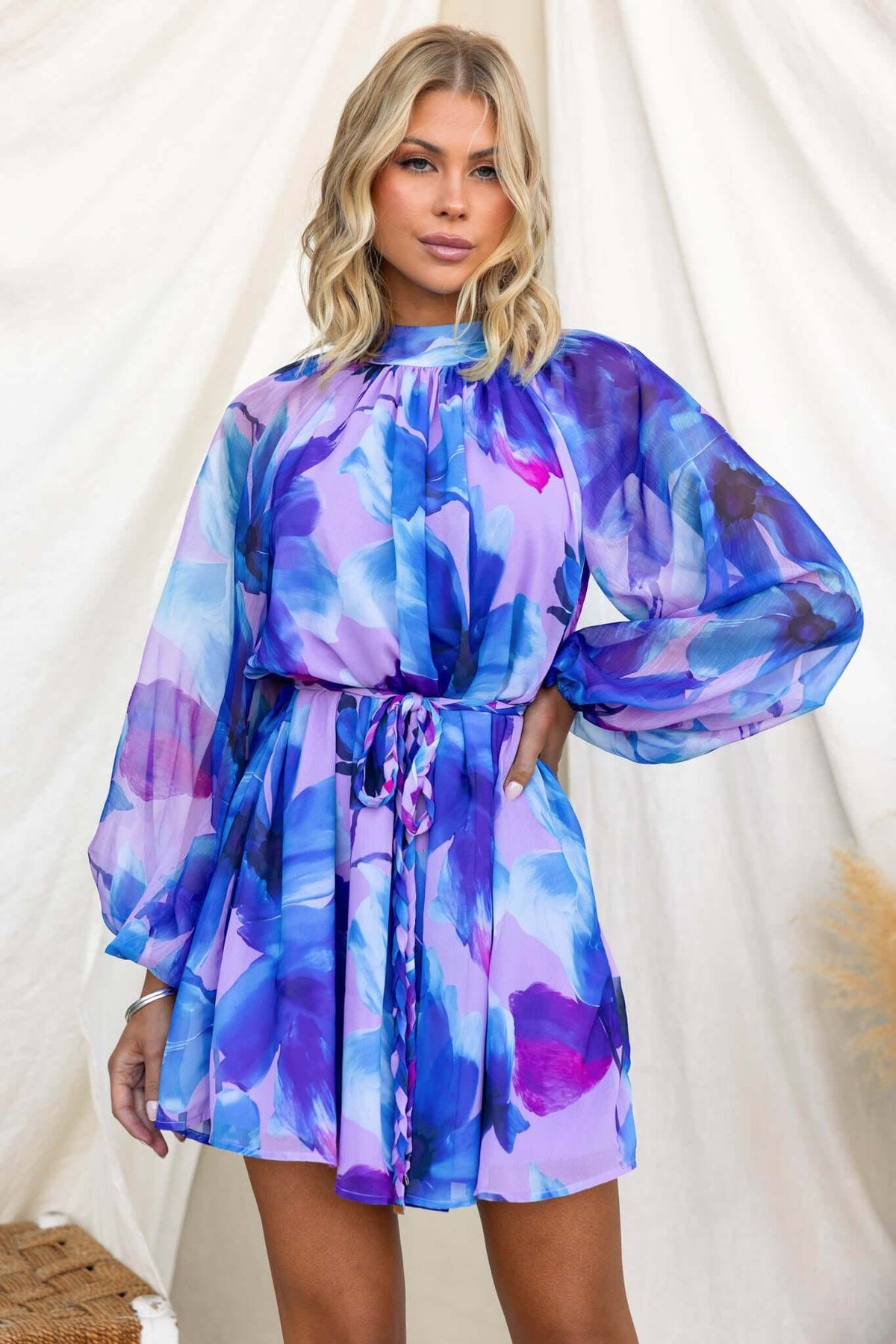 Model showcasing a vibrant, floral Siletto Dress with high neckline and elastic cuffs.