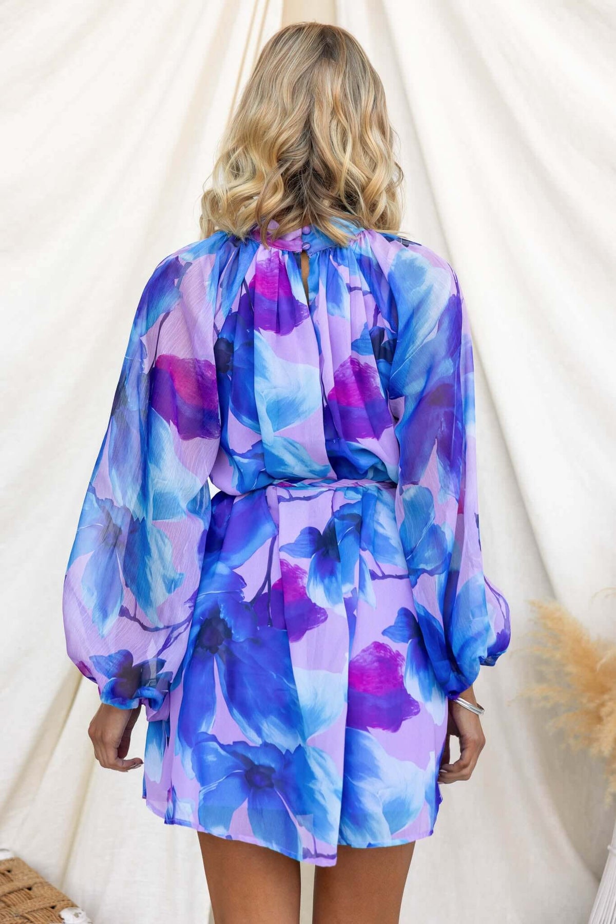 Back view of a model wearing the Siletto Dress with vibrant blue and purple floral print.