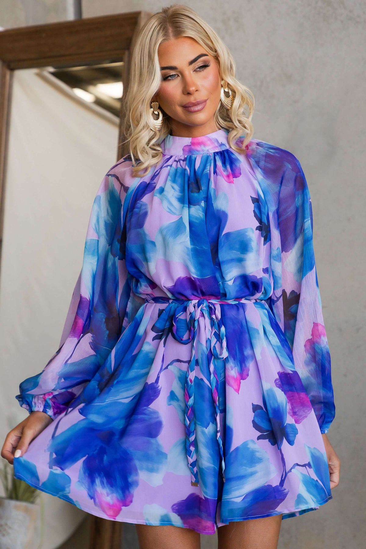 Model showcasing the Siletto Dress with floral print and high neckline, featuring elastic cuffs and a removable tie.