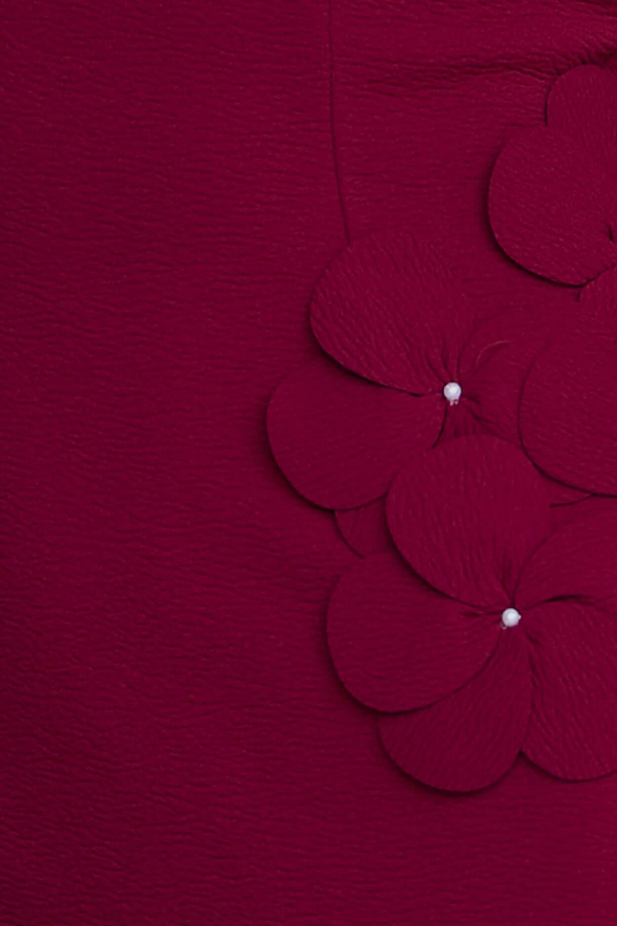 Close-up of Sofia Maxi Dress showing textured fabric and flower embellishment in rich burgundy color.