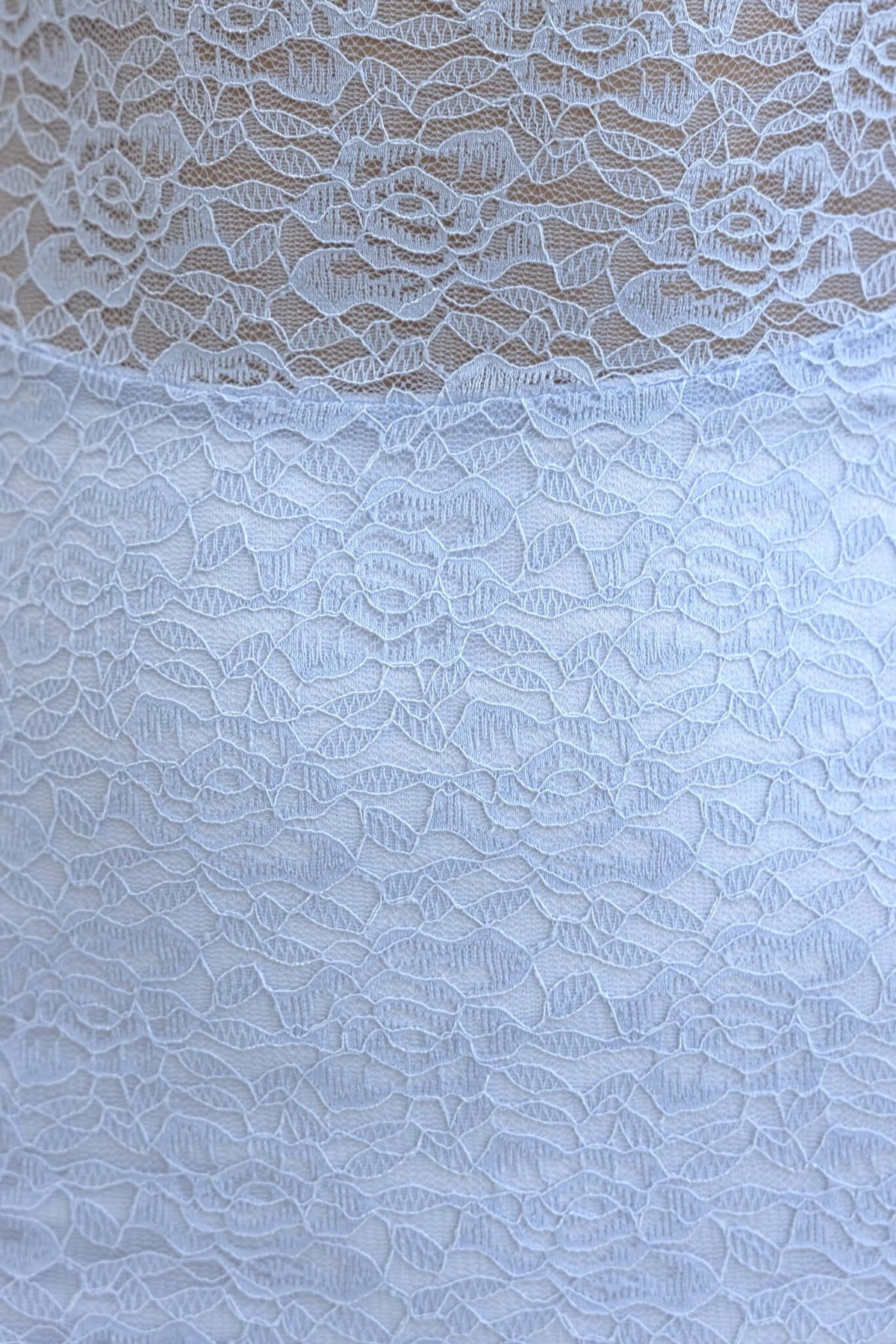 Close-up of Sumba Maxi Dress lace material featuring intricate floral patterns in light blue.