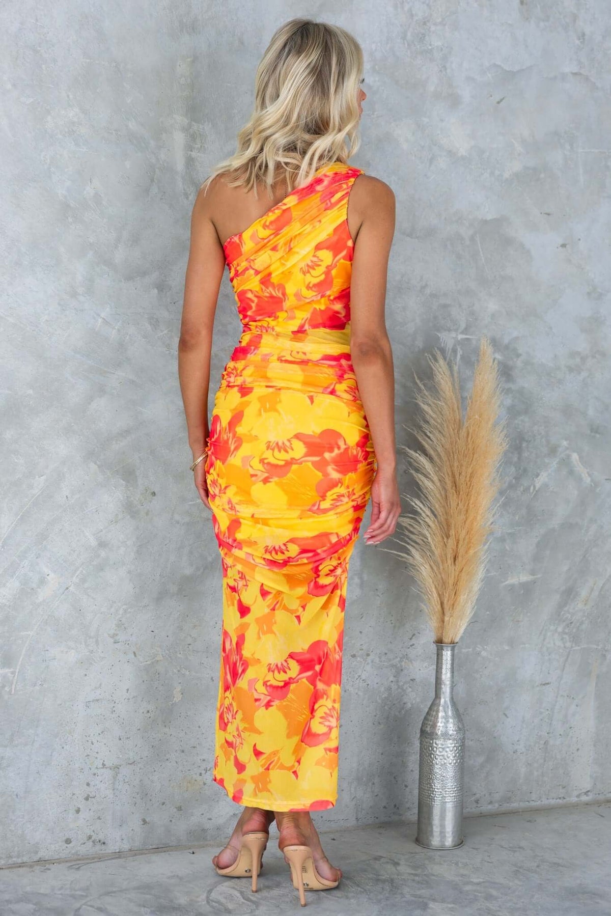 One-shoulder sundara maxi dress in vibrant orange and yellow floral pattern, featuring a side zip and mesh overlay.