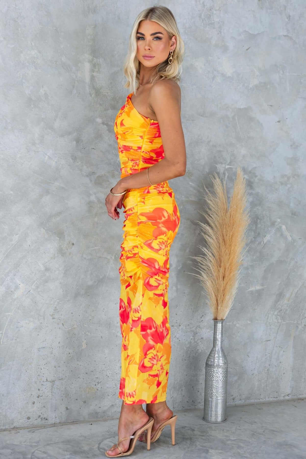 Sundara Maxi Dress in vibrant yellow and orange floral print, featuring a one-shoulder neckline and fitted silhouette.