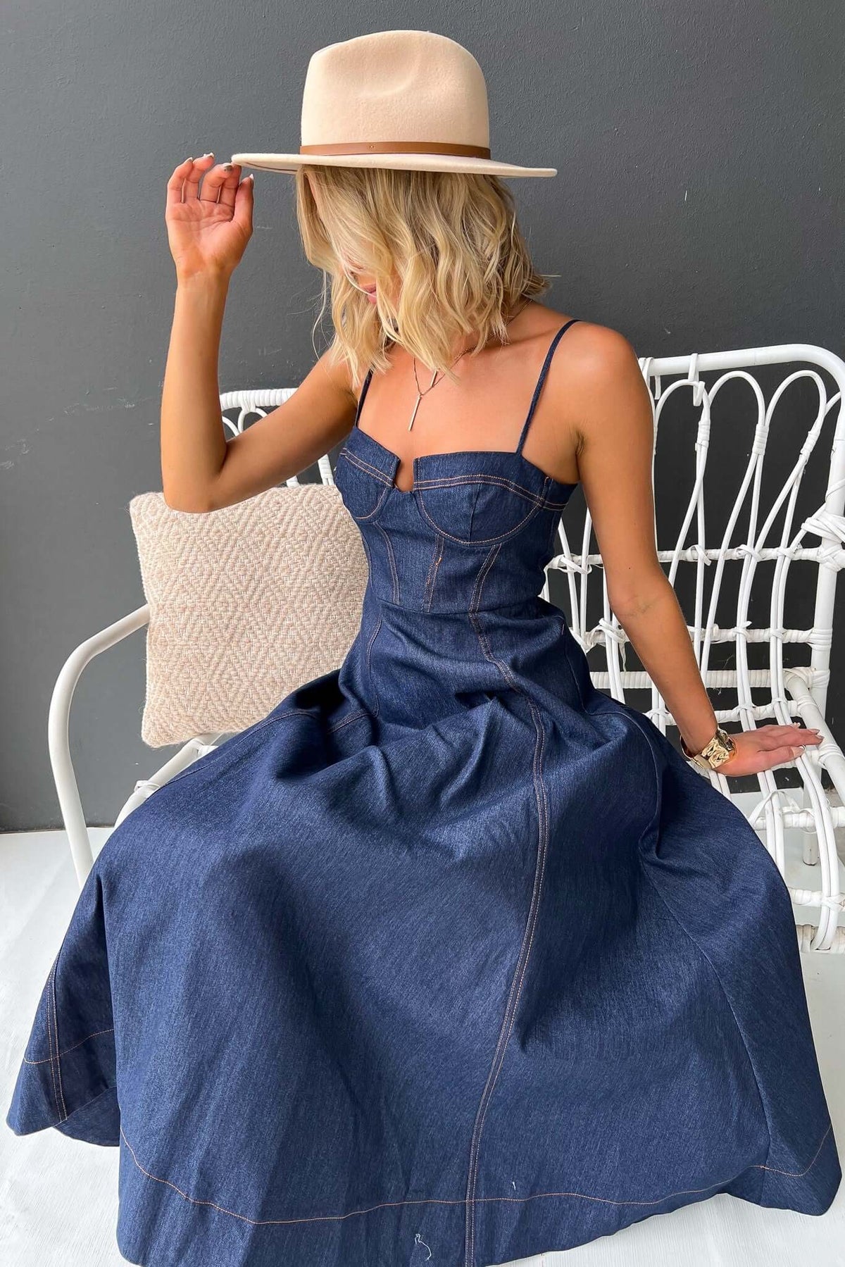 Sylvi Denim Midi Dress with adjustable straps and boning, styled with a hat, perfect for casual outings.