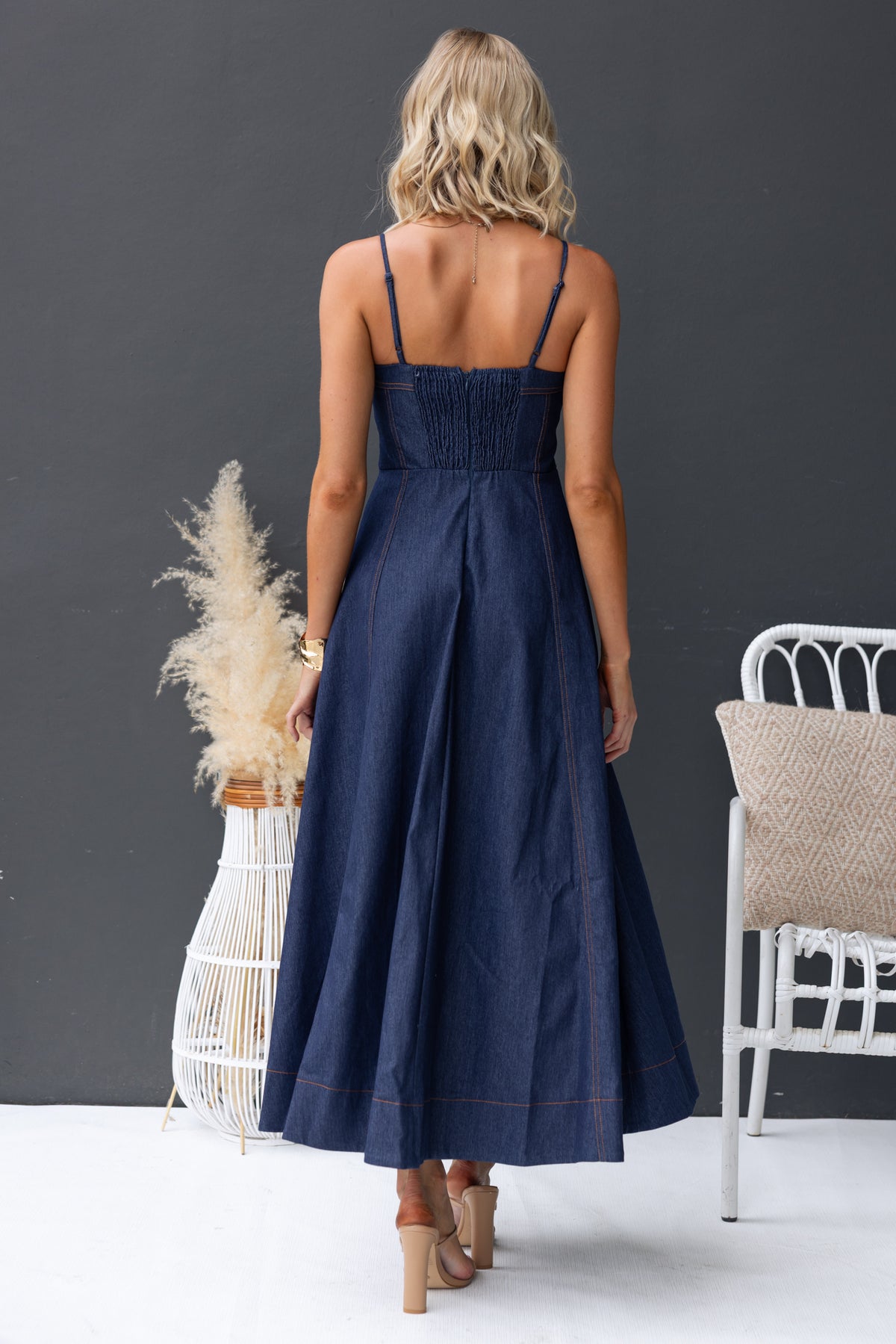 Back view of Sylvi Denim Midi Dress with adjustable straps and flowing design, styled with a boho setting.