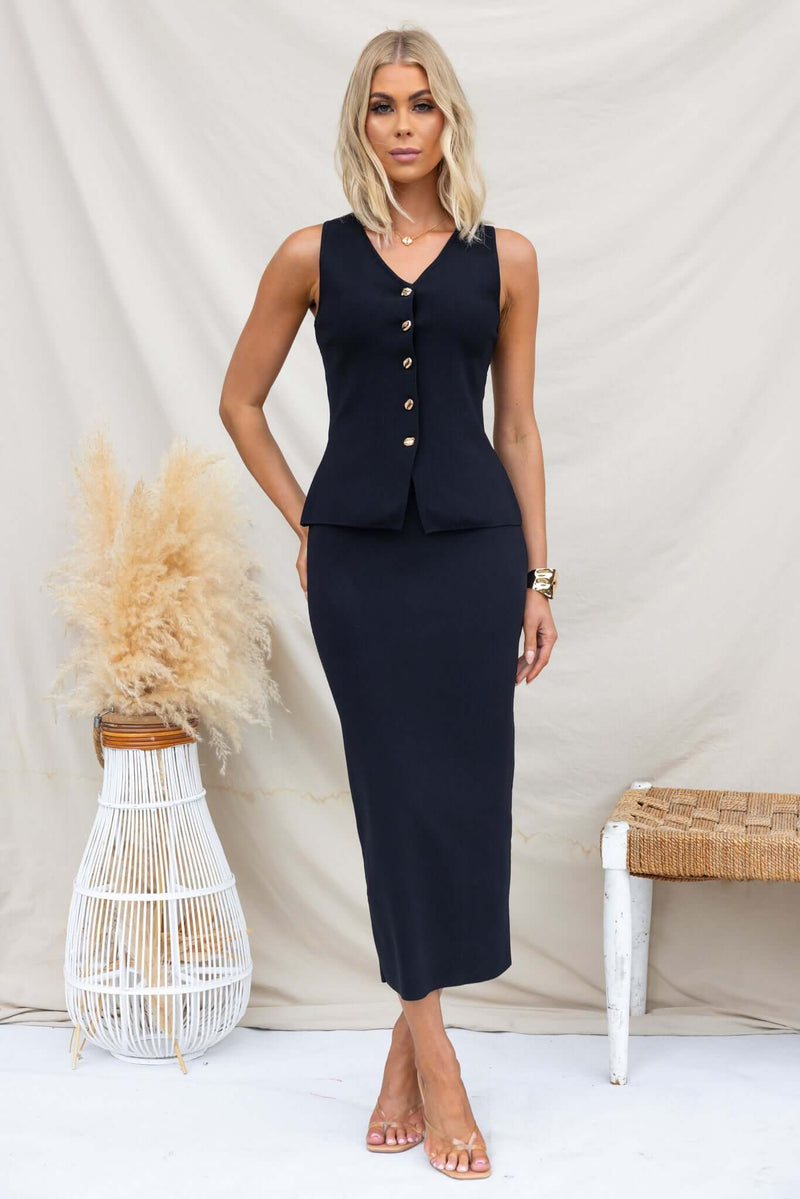 Model wearing Tammie Midi Skirt in black, mid-high waist fit with elastic waistband, showcasing knit stretch material.