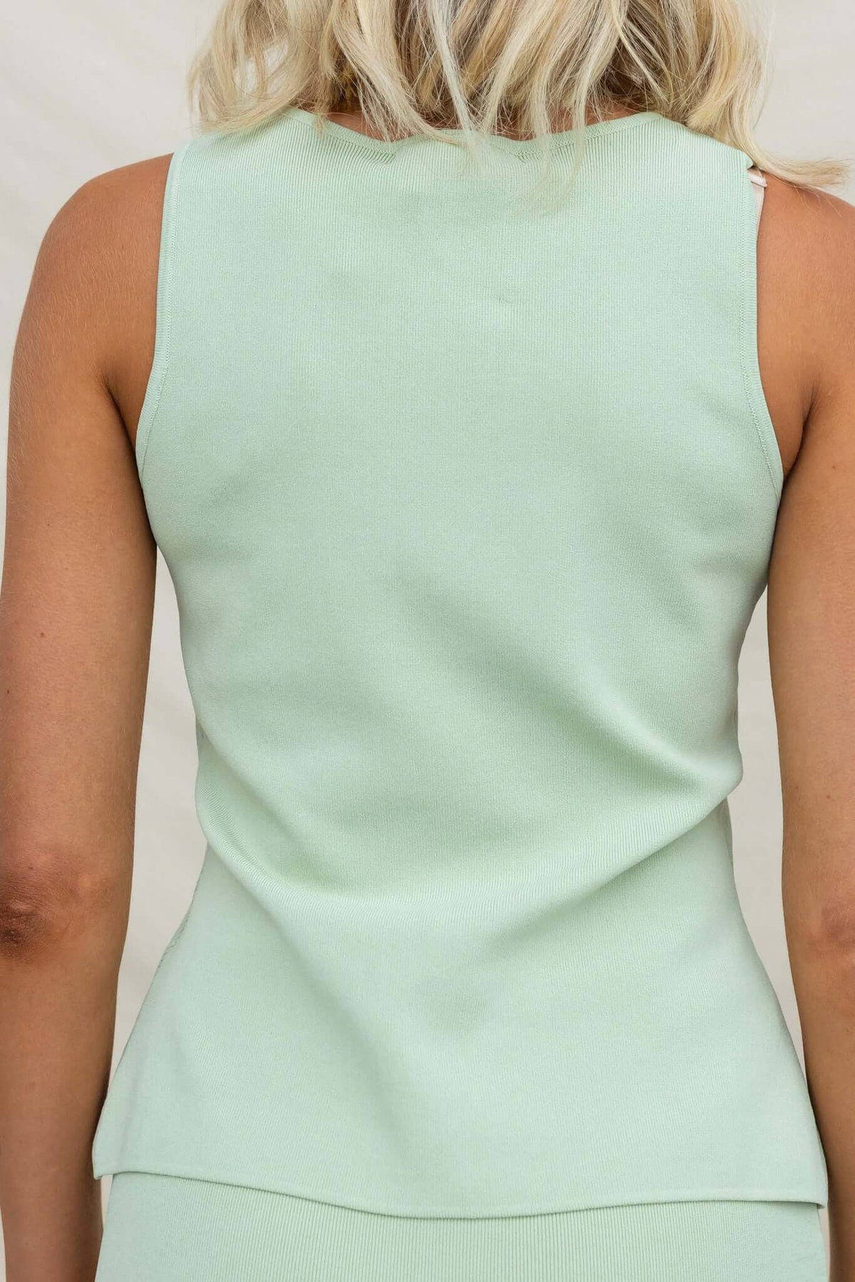 Back view of Tammie Top in light green knit material, featuring a button-up design and stretchy fabric.