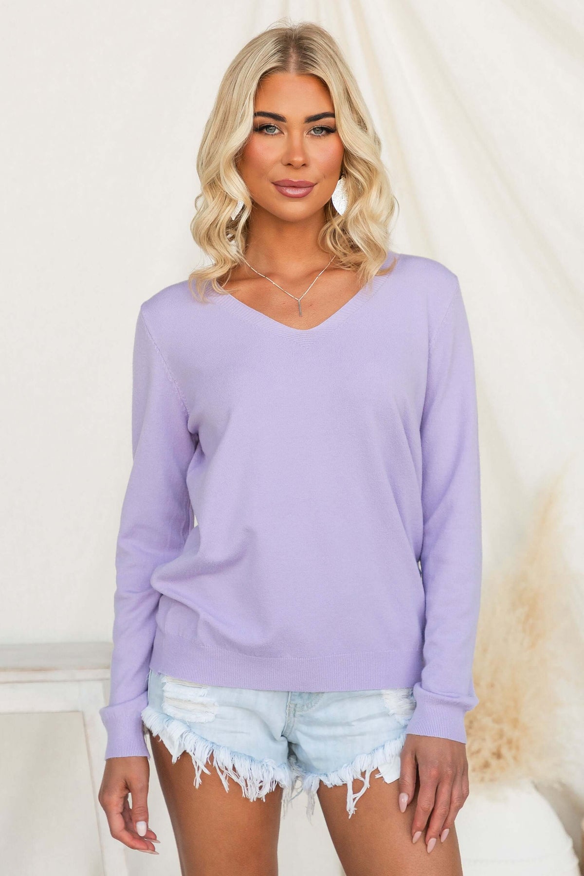 Model wearing Tayla Top in lavender with V-neckline and relaxed fit, styled with denim shorts.