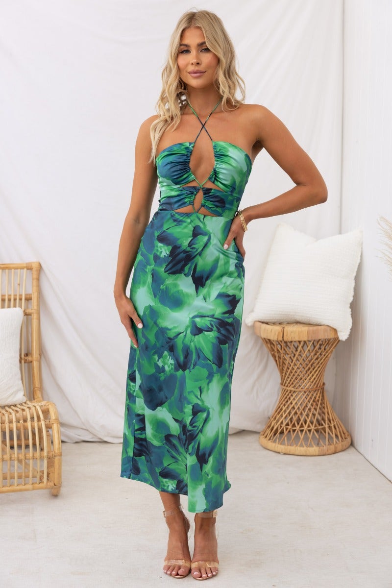 Model wearing Meghan Midi Dress with satin look, adjustable tie neckline, and floral green print.