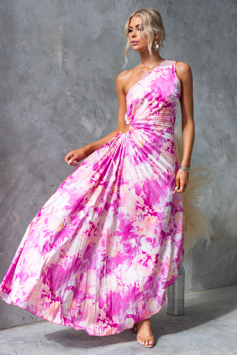 Model wearing a pink floral Tejano maxi dress with a one-shoulder neckline and side cut-out tied at the waist.