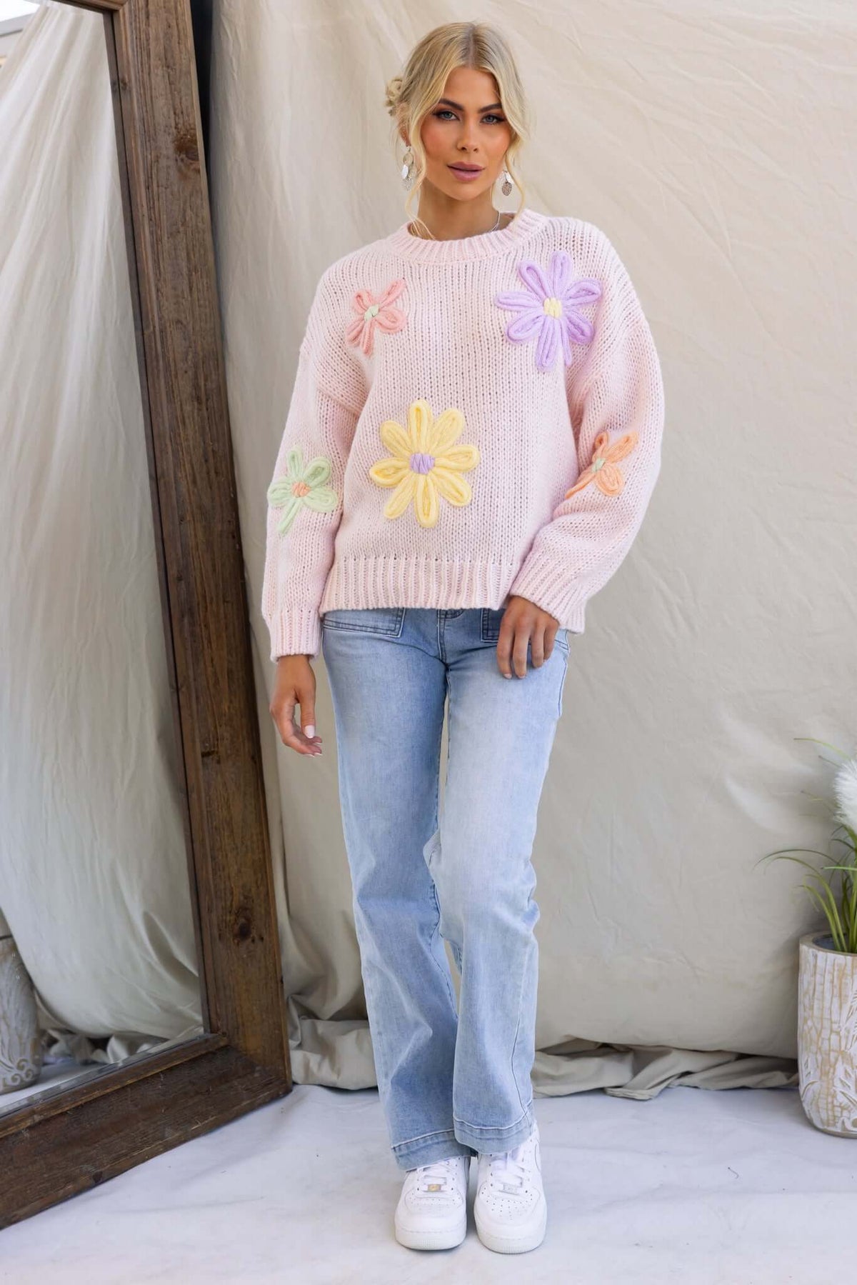 Model wearing the Thought Of You Jumper, a pink knit jumper with embroidered flowers, styled with light jeans.