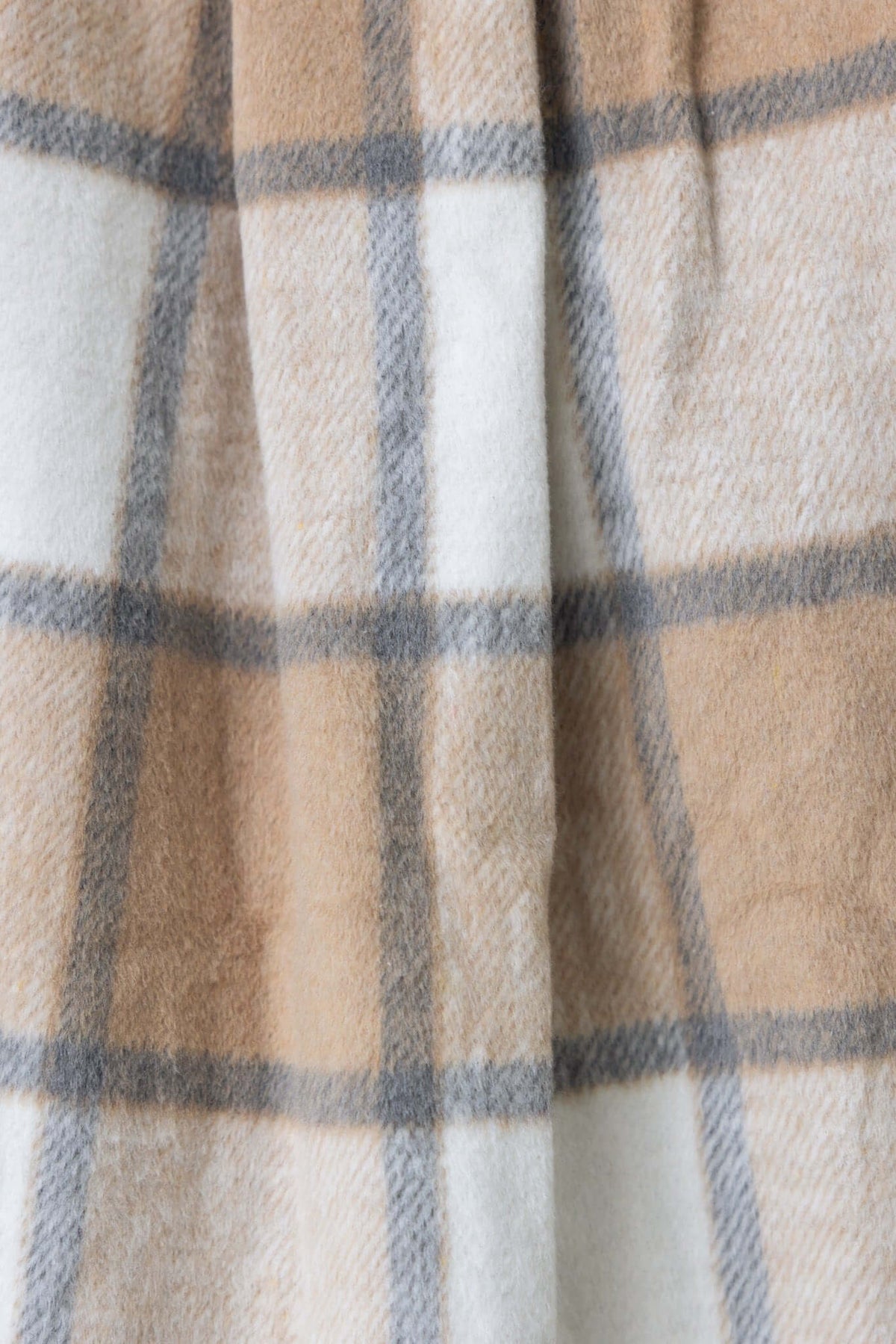 Close-up of fabric texture featuring a beige and white plaid pattern, perfect for a stylish shacket.
