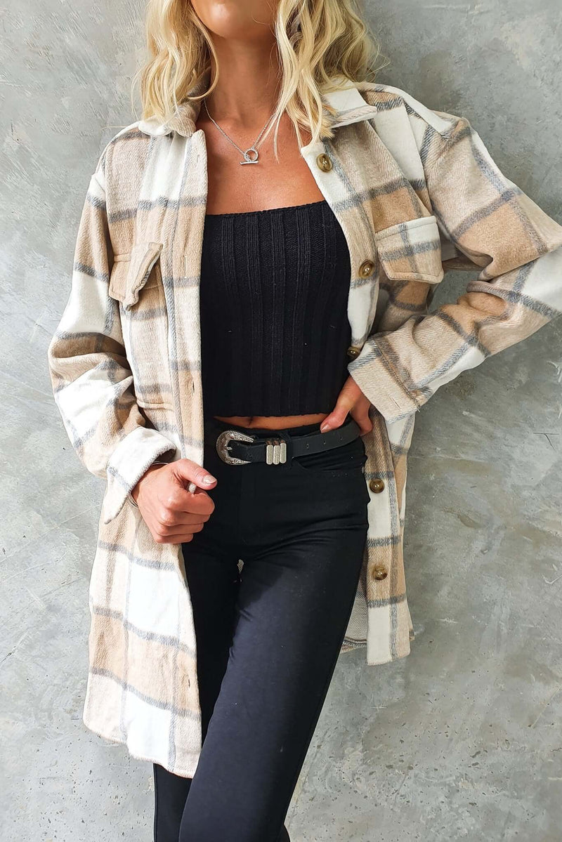 Woman wearing a plaid Torres shacket with button-up front, displayed over a black top and styled with black jeans.