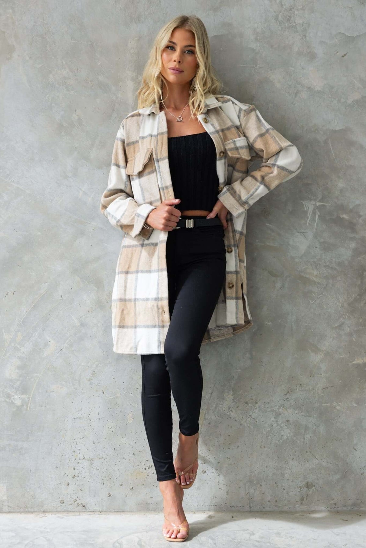 Model wearing a beige and white plaid Torres Shacket, styled with black leggings and a fitted top.