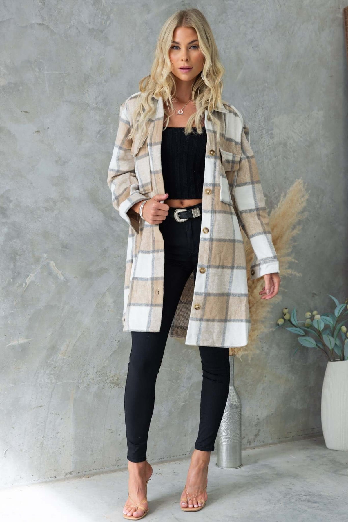 Model wearing the Torres Shacket, a plaid button-up jacket with pockets, styled with black leggings and a top.
