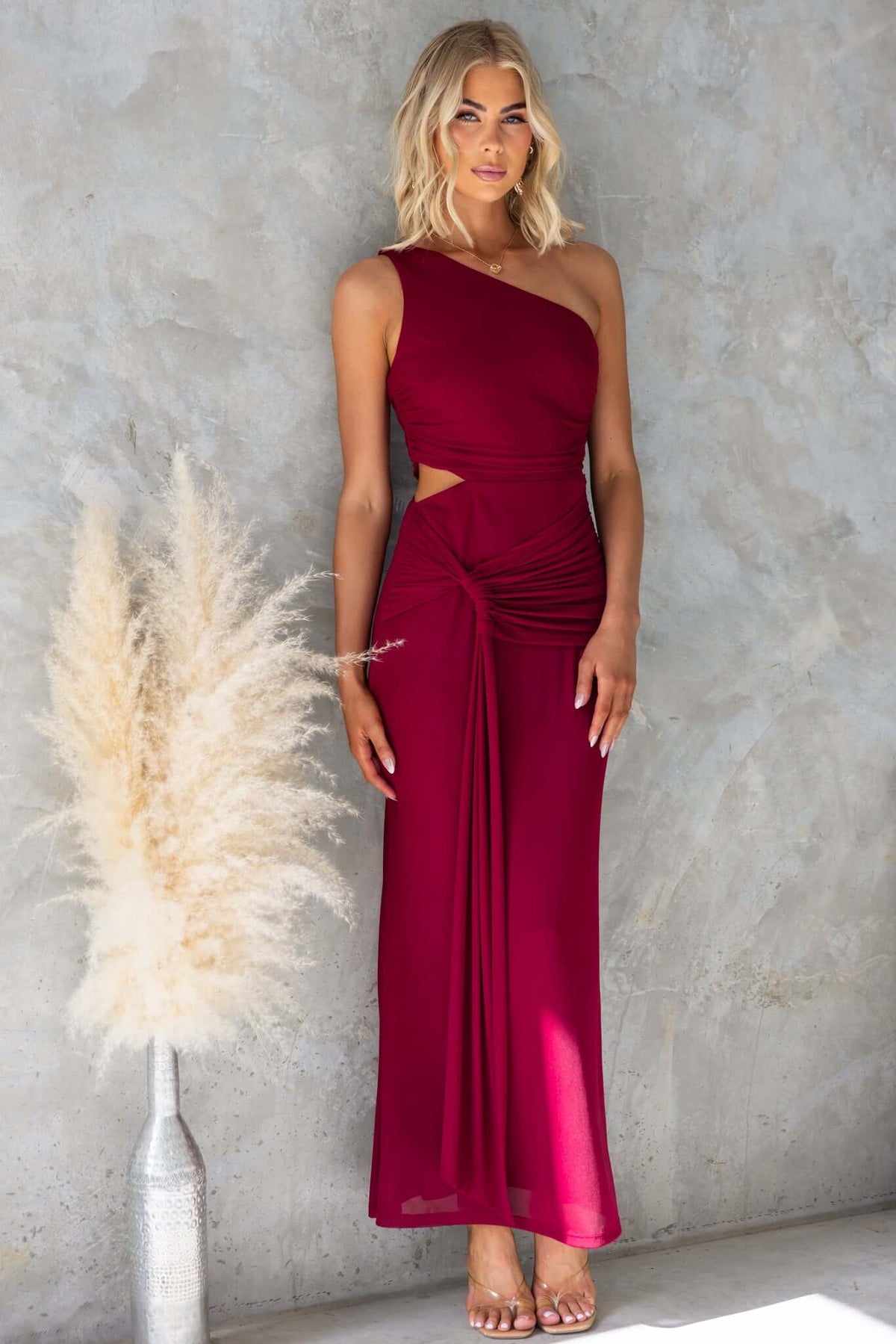 Elegant one-shoulder burgundy maxi dress with cut-out waist and side zip, perfect for formal occasions.
