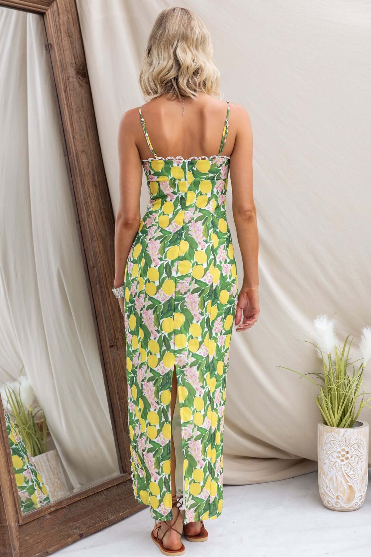 Woman wearing Umeeka Maxi Dress with lemon print, adjustable straps, and back split.