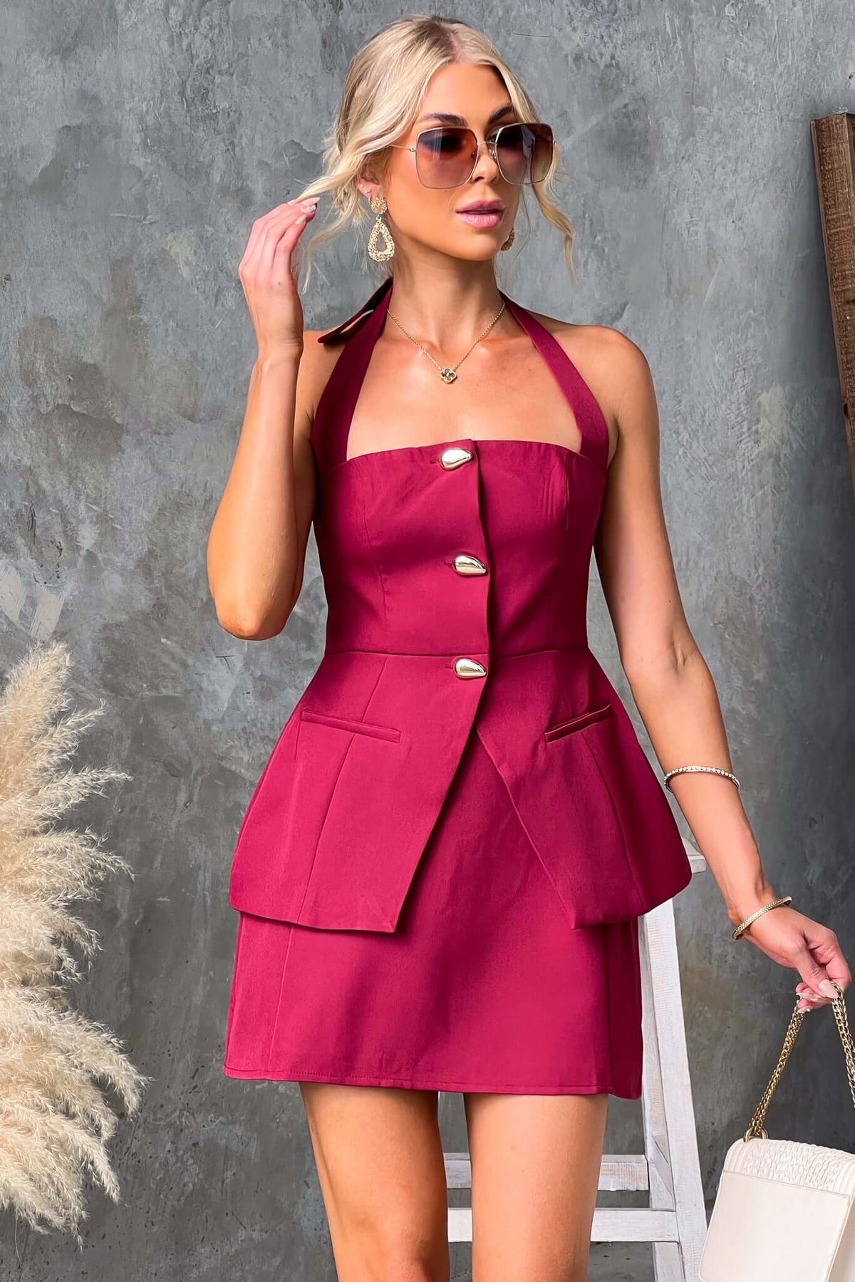 Model wearing Varis Top in burgundy with halter neckline, button-up front, and faux pockets, styled for a chic look.