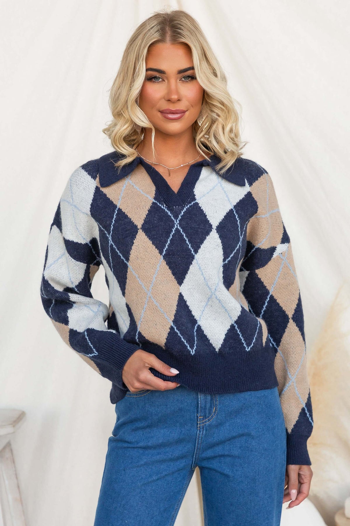 Model wearing the Vella Jumper featuring a navy knit design with a collar and diamond patterns.