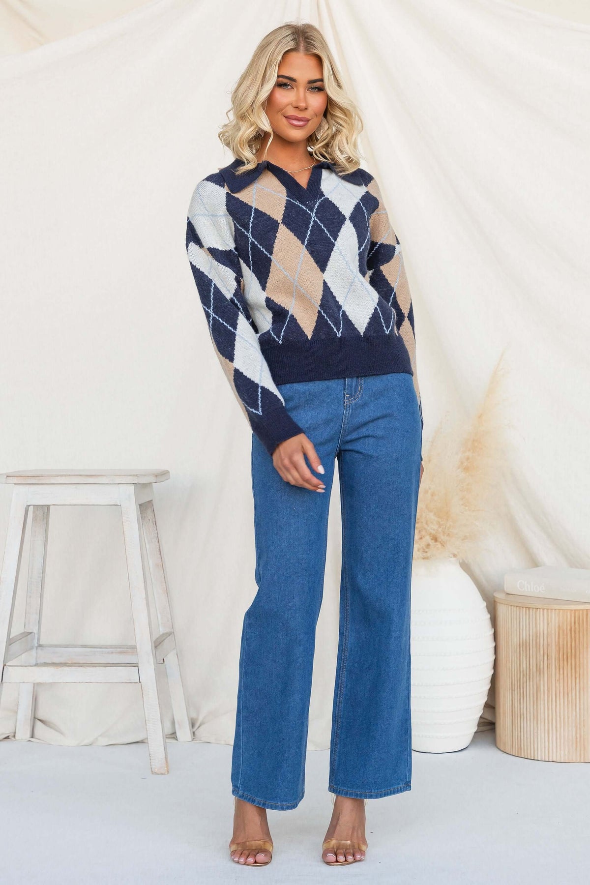 Model wearing Vella Jumper featuring navy knit, collar, and stylish design with denim pants.
