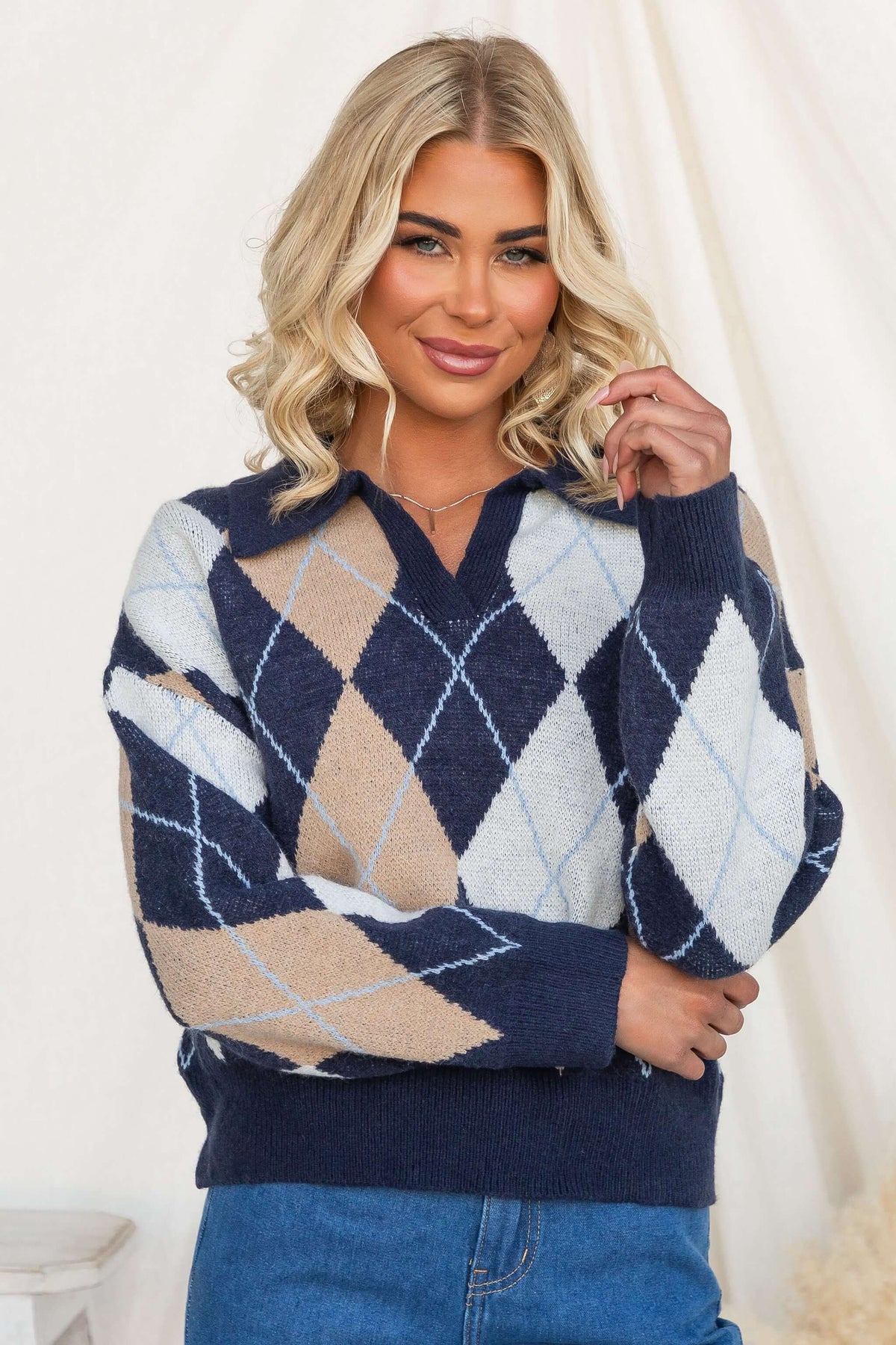 Model wearing Vella Jumper, a navy-based knit jumper with a collar and diamond pattern, displaying style and comfort.