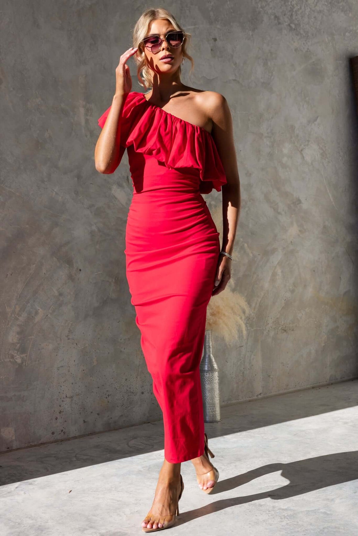 Model wearing a red Vitoria Maxi Dress with one-shoulder neckline and ruffles, showcasing a stylish fit.