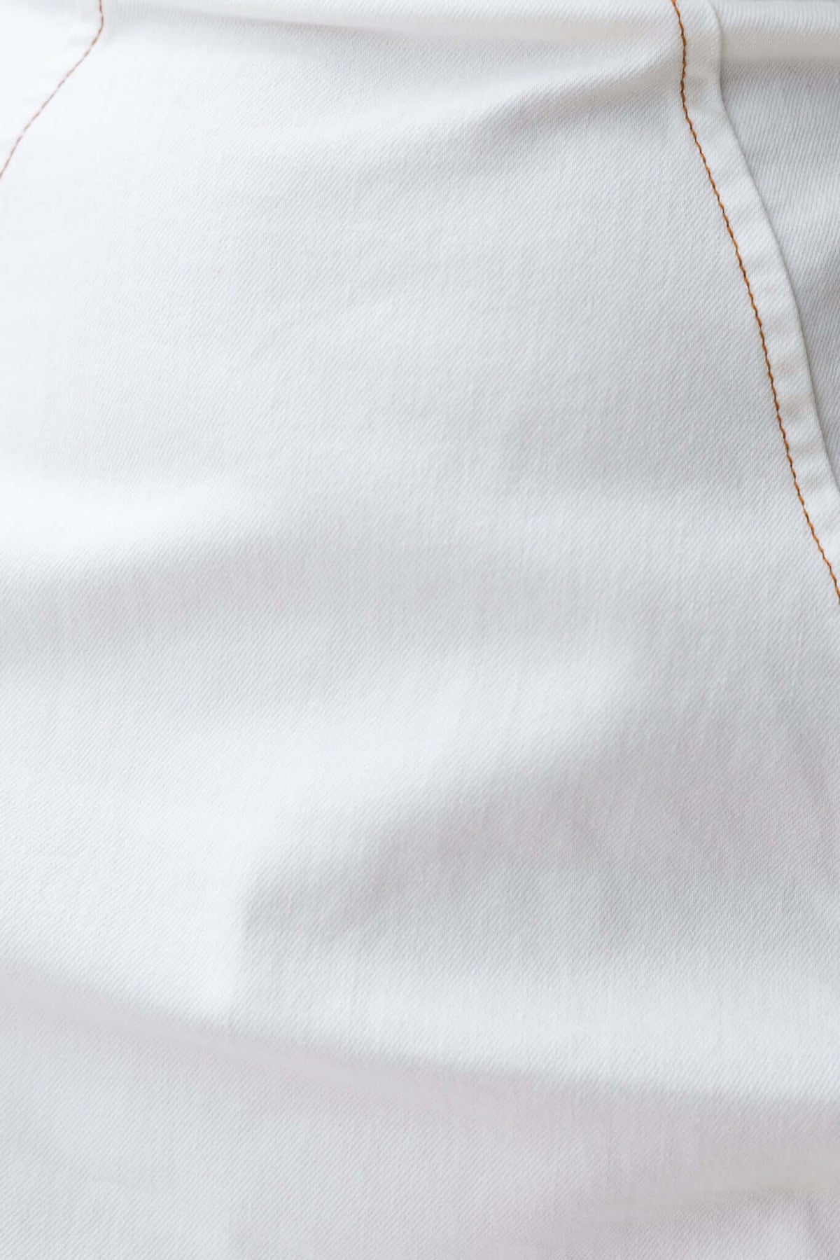 Close-up of soft white fabric with visible stitching details, showcasing fine texture and quality.