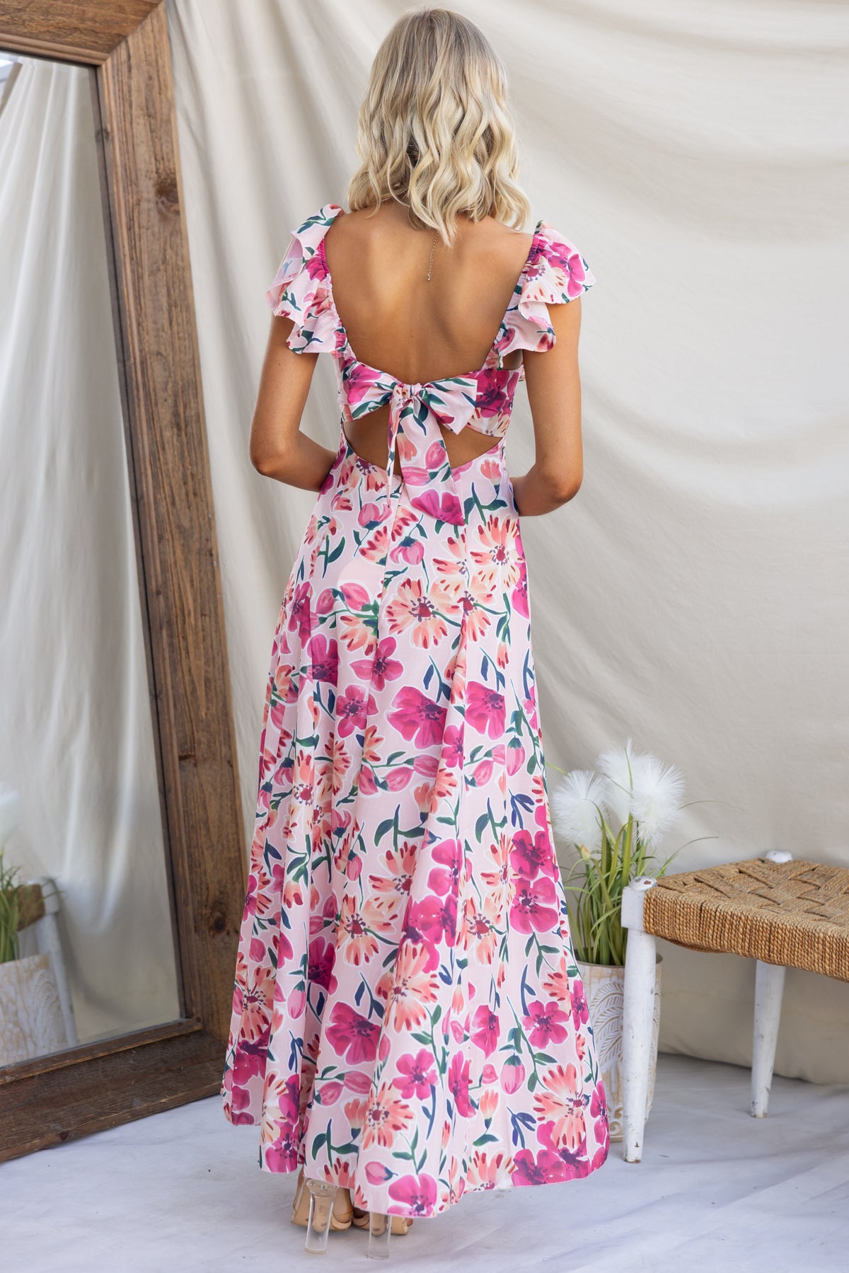Back view of Wilma Maxi Dress featuring floral print, tie detail, and ruffled sleeves, styled for summer occasions.