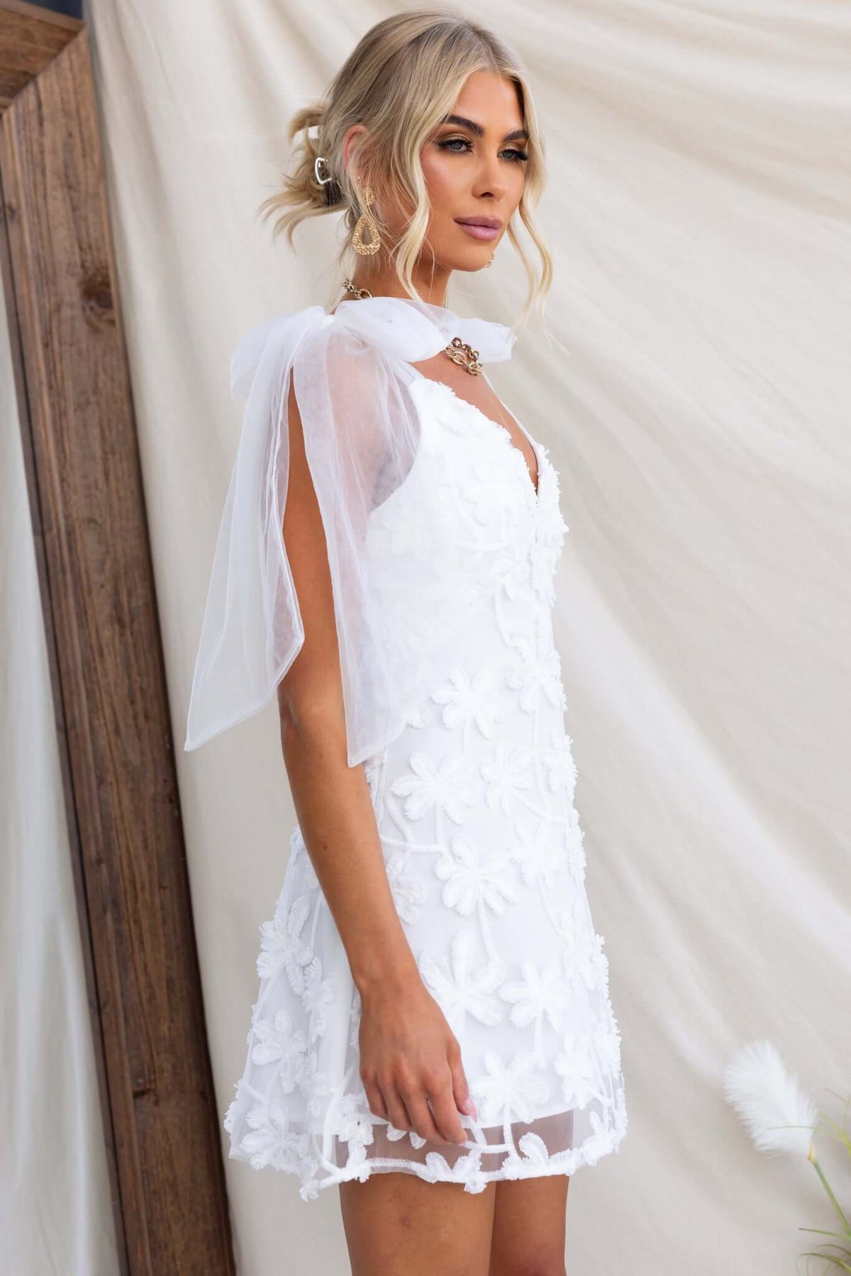 Model wearing the Xaria Dress, a white tulle embroidered mini dress with tie straps and a back zip.