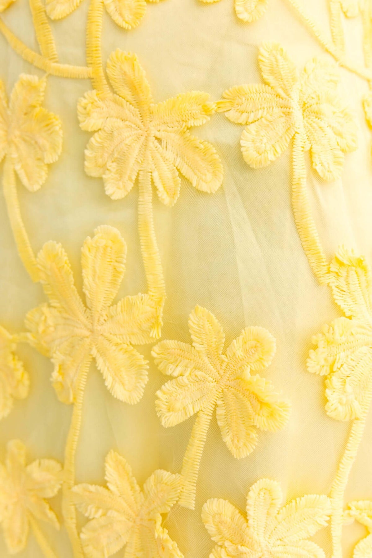 Close-up of embroidered yellow tulle fabric featuring floral patterns for the Xaria Dress.